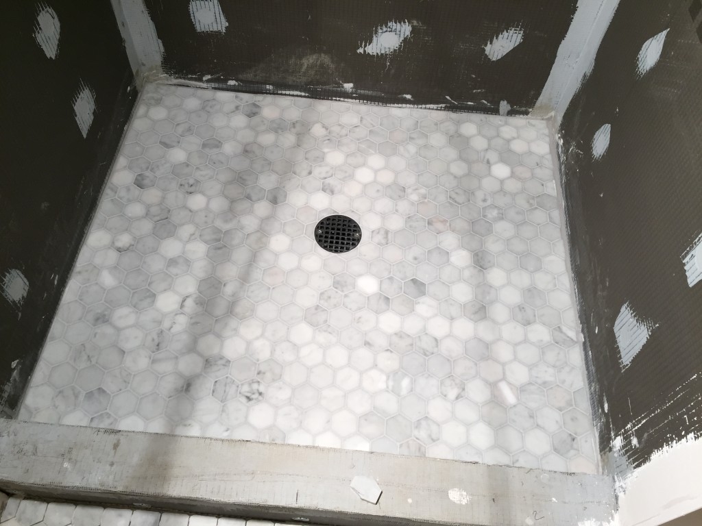 {...and the shower floor is done and grouted! We ended up selecting a much lighter grout than we expected to based on how the different grouts look and the recommendation of the tile contractor to avoid something too dark.}
